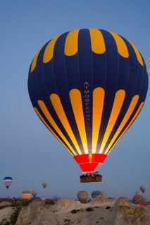 Balloons of different colours rise calmly into the morning atmosphere over the vast terrain, Göreme