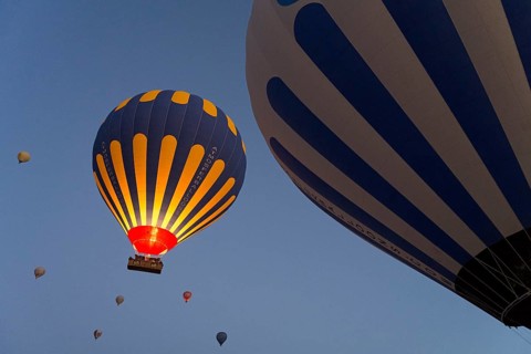 Hot air balloons in blue and yellow stand out against the morning sky, Göreme National Park, Göreme