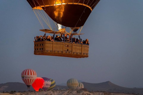 A hot air balloon with passengers in the basket floats under the morning sky, Göreme National Park,