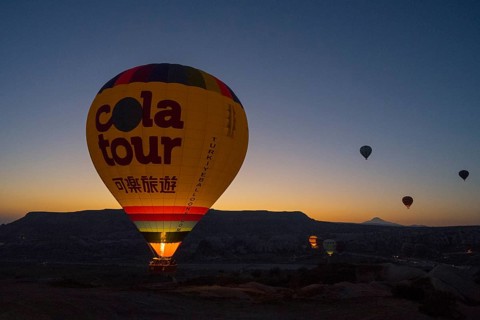 A colourful hot air balloon rises into the quiet sky at sunrise, Göreme National Park, Göreme