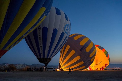 Hot air balloons are illuminated at night while the sky in the background is dark, Göreme National