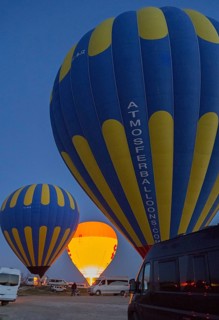 Hot air balloons stand ready at dusk, illuminated against a dark sky, camper, motorhome, Göreme