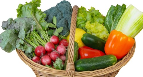 A wicker basket overflowing with a colorful array of fresh vegetables, including radishes, lettuce,