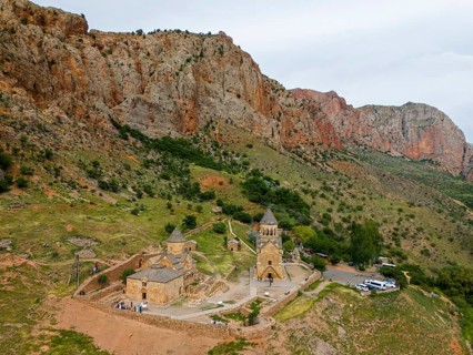 Church landscape in front of dramatic rock formations, surrounded by green nature, in a secluded
