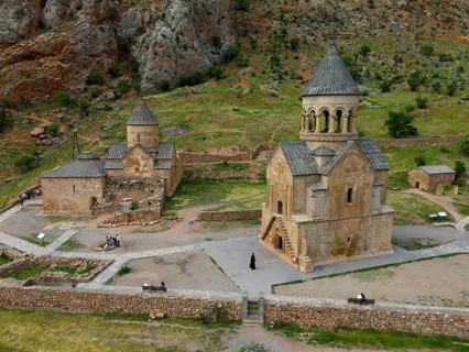 Old church in rural area with stone buildings and green landscape surrounded by mountains, aerial