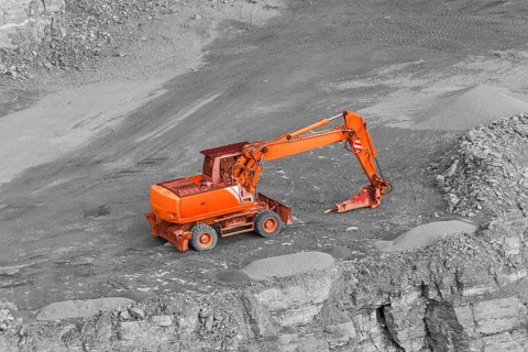 Tracked red excavator in rocky quarry ambiance