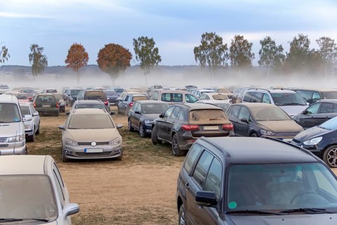 Dusty parking space scenery on a field including lots of dust covered cars at evening time in