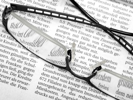 Newspaper detail with pair of glasses