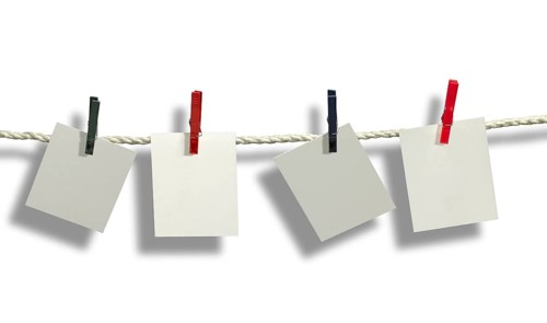 Clothesline with some light grey labels fixed with clothes pins in front of white back with shadow