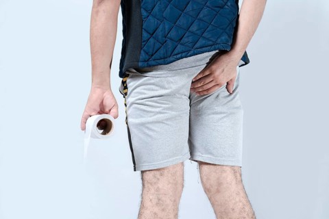Man with diarrhea holding toilet paper an his anus