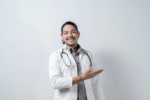 Smiling doctor showing to the right. Doctor pointing to his right