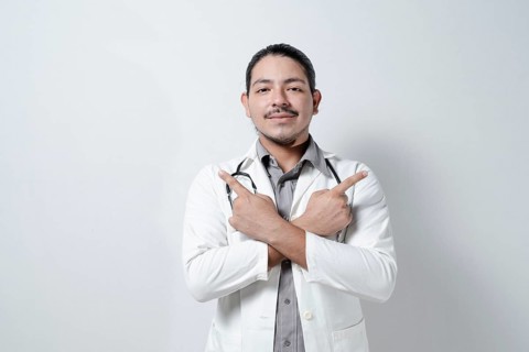 Young doctor pointing up to both sides on isolated