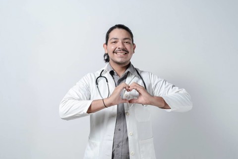 Smiling doctor making heart symbol on isolated