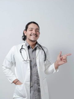 Smiling young doctor pointing to the right on isolated