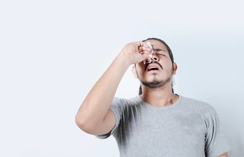 Young man with nosebleed on isolated background. Person with sinusitis or epistaxis. Concept of a