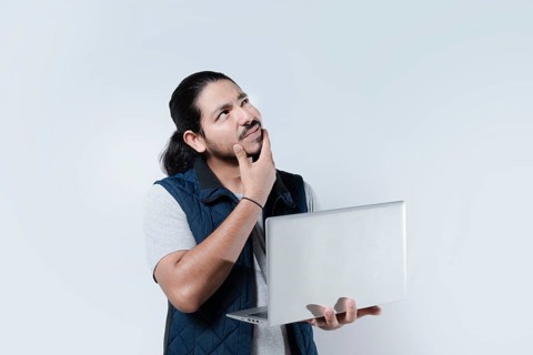 Thoughtful man with hand on chin using computer on isolated background. Man thinking holding a