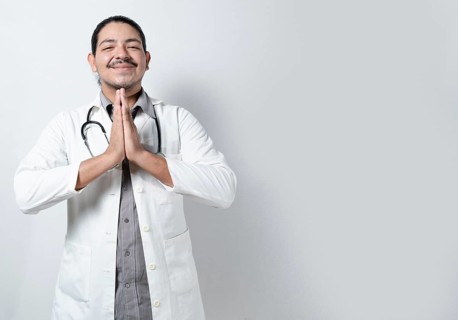 Smiling doctor praying on isolated. Young doctor praying