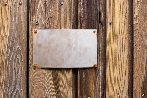 Old metallic sign on wooden board