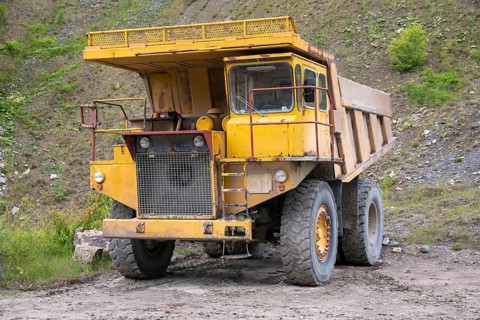 Yellow haul truck in a quarry at summer time