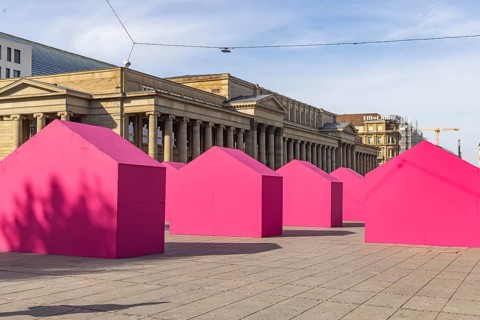 Twelve houses in bright magenta stand on Stuttgart's Schlossplatz in front of the art museum. The