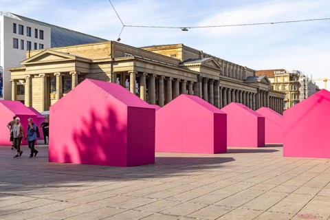 Twelve houses in bright magenta stand on Stuttgart's Schlossplatz in front of the art museum. The