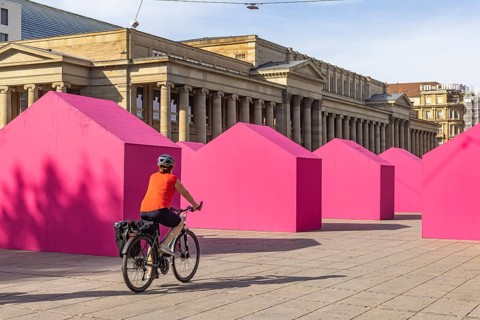 Twelve houses in bright magenta stand on Stuttgart's Schlossplatz in front of the art museum. The
