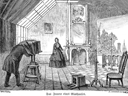 The interior of a glass house, portrait photographer with view camera on tripod, wooden tripod,