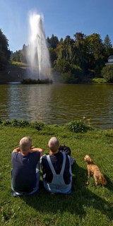 Couple with dog at the water games at the big pond with the high rising fountain, Bergpark
