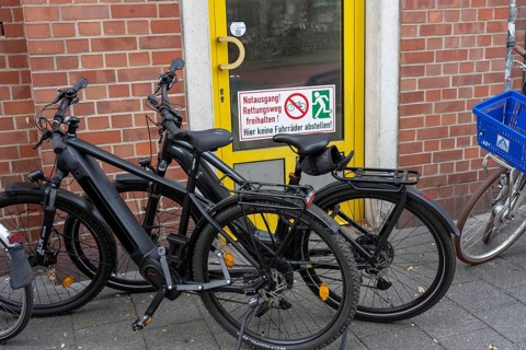 Bicycle traffic in Münster, bicycles parked on the pavement, in front of an emergency exit, which