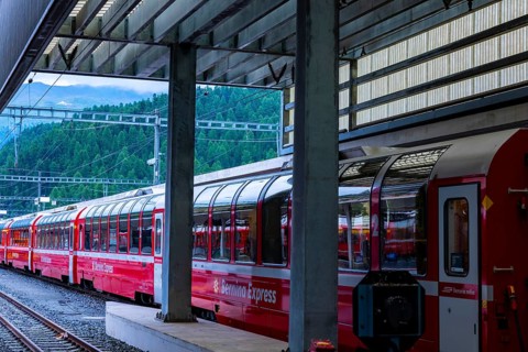 Railroad Station and Red Bernina Express Train with Mountain View in a Sunny Summer Day in