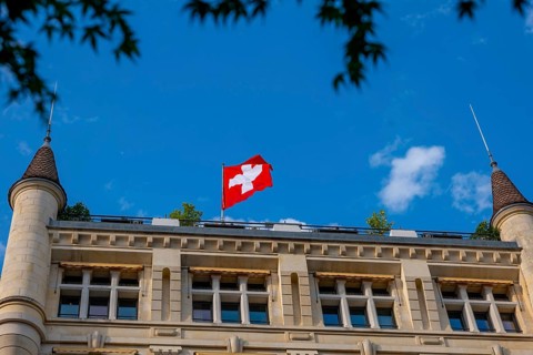 Beautiful Swiss Flag on a Old Building with Towers Against Blue Sky in a Sunny Summer Day in
