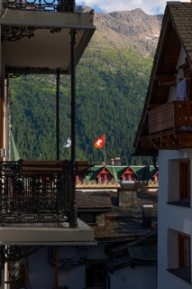 Beautiful City with Swiss and Grisons Flag and House and Mountain in the Swiss Alps with Blue Sky