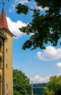 House with Tower and Beautiful Bridge and Tree Branch in a Sunny Summer Day in City of Fribourg,