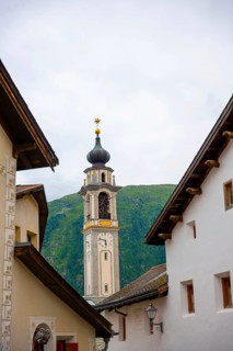 Beautiful Street in Old Town with Mountain View and Church Tower in a Summer Day in Samedan,