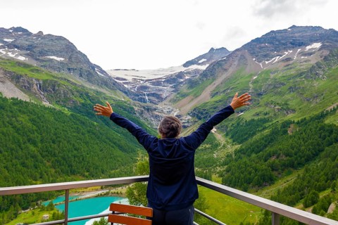 Woman with Arms Outstretched over the Beautiful Mountain Alp Grüm with Glacier and Alpine Lake Palü