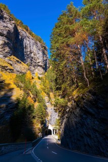 Mountain Road with Tunnel and Tree in the Swiss Alps in Mountain Valley in a Sunny Autumn Day with