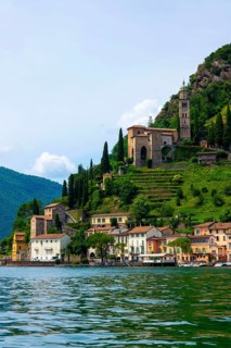 House and Church on Mountain Range in a Sunny Summer Day on the Waterfront to Lake Lugano in