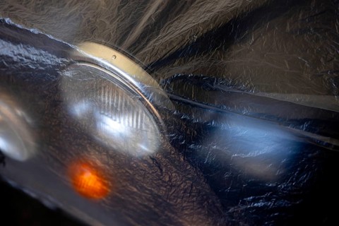 Car Lamps on the Front of a an Old Classic Car Covered with Plastic Protection in Switzerland