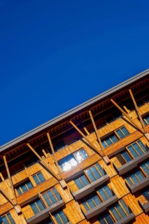 Beautiful Modern Wood Facade Building with Balcony Against Blue Clear Sky in a Sunny Summer Day in