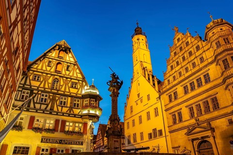 Georgsbrunnen, Marien-Apotheke, town hall and town hall tower in Rothenburg ob der Tauber at dusk,