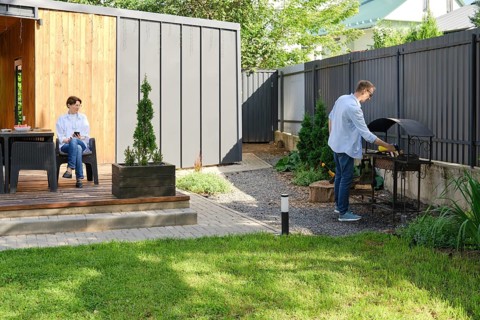 A couple spends the day outdoors at their contemporary home. The wife is seated on a patio, while