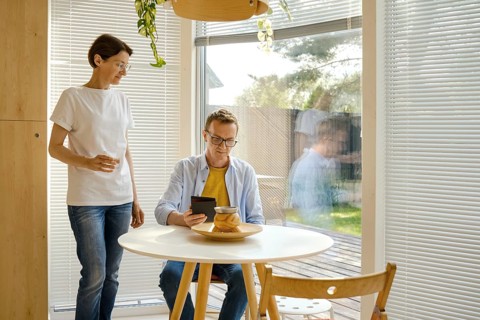 Two people relax in a modern indoor space filled with natural light. One person stands nearby