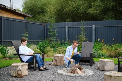 Middle-aged couple enjoy a relaxing evening in a backyard, sitting by a campfire surrounded by