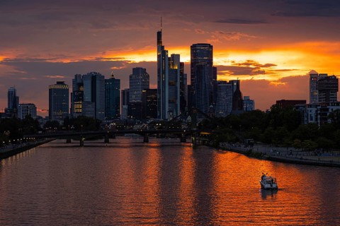 The sun breaks through the clouds behind the Frankfurt banking skyline shortly in front of setting,