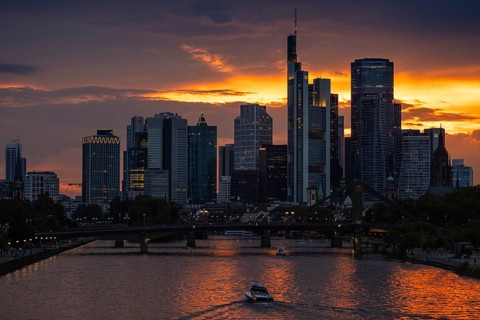 The sun breaks through the clouds behind the Frankfurt banking skyline shortly in front of setting,
