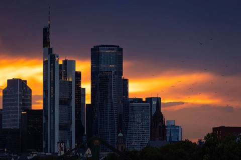 The sun breaks through the clouds behind the Frankfurt banking skyline shortly in front of setting,