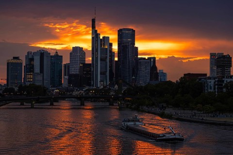 The sun breaks through the clouds behind the Frankfurt banking skyline shortly in front of setting,