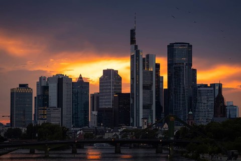 The sun breaks through the clouds behind the Frankfurt banking skyline shortly in front of setting,