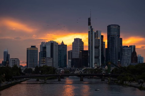The sun breaks through the clouds behind the Frankfurt banking skyline shortly in front of setting,