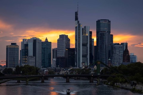 The sun breaks through the clouds behind the Frankfurt banking skyline shortly in front of setting,